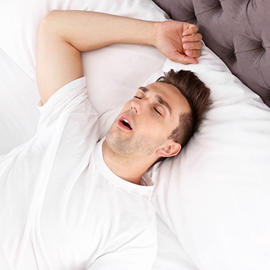 Man in white shirt lying in bed snoring