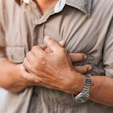 Man with heart problems gripping his chest